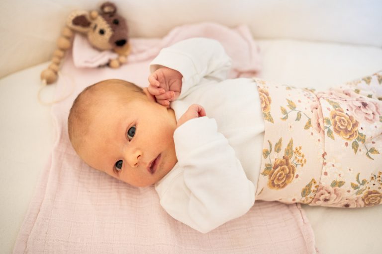 ein neugeborenes Mädchen schaut neugierig in die Kamera.