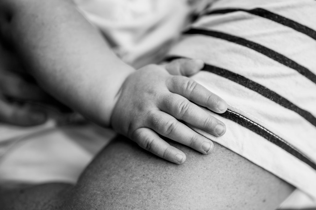 Babyhand auf Mamas Oberarm