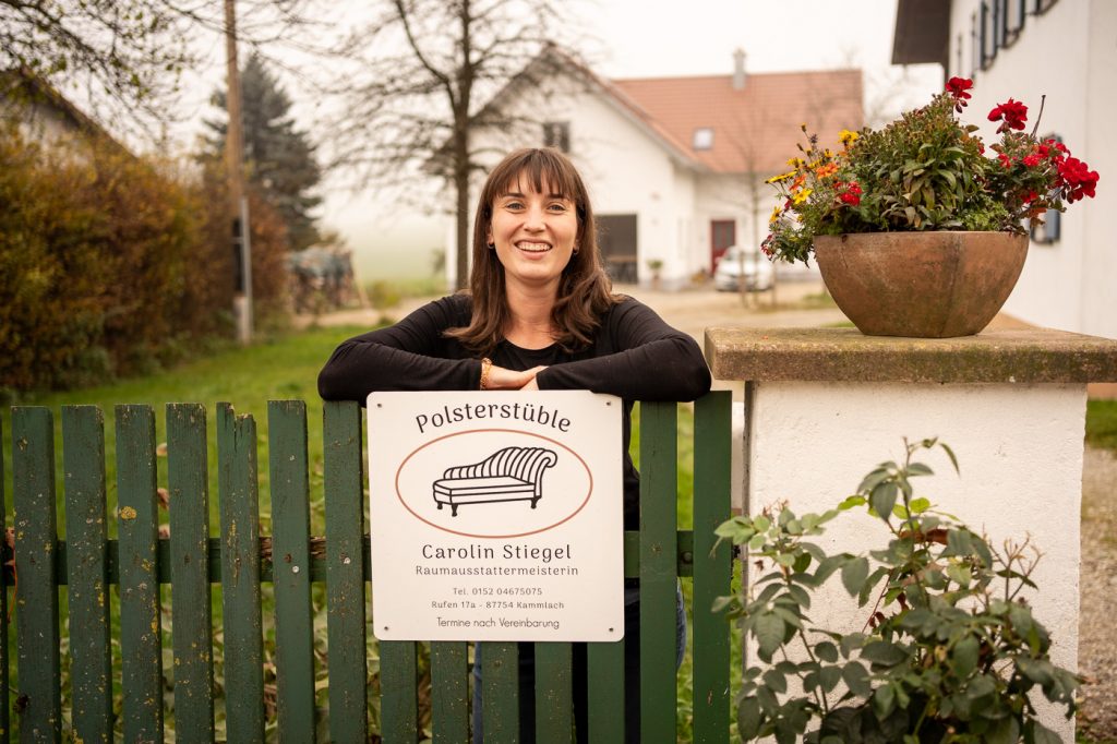 Carolin Stiegel vom Polsterstüble in Rufen lehnt am Zaun und lacht in die Kamera.